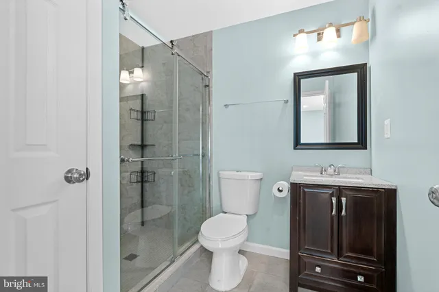 a bathroom with a toilet sink vanity granite and shower