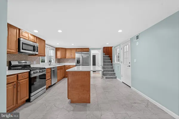 a large kitchen with stainless steel appliances granite countertop a stove top oven a sink and a refrigerator