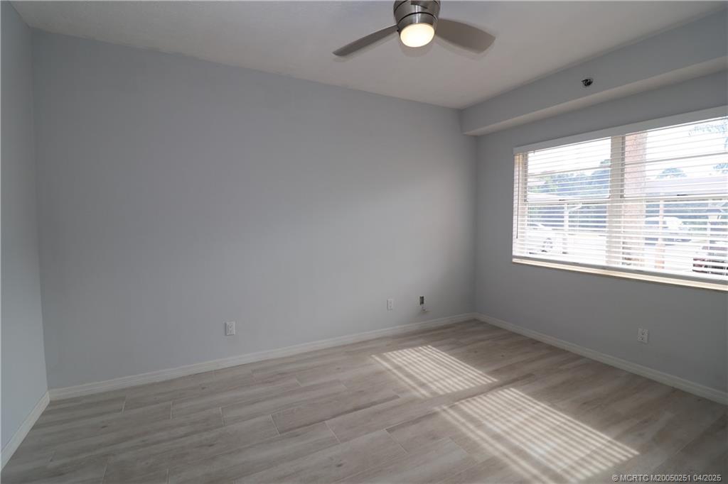 2950 Southeast Ocean Boulevard, Unit 101 Stuart, FL 34996 - Photo 21 of 35 a view of an empty room with wooden floor and windows