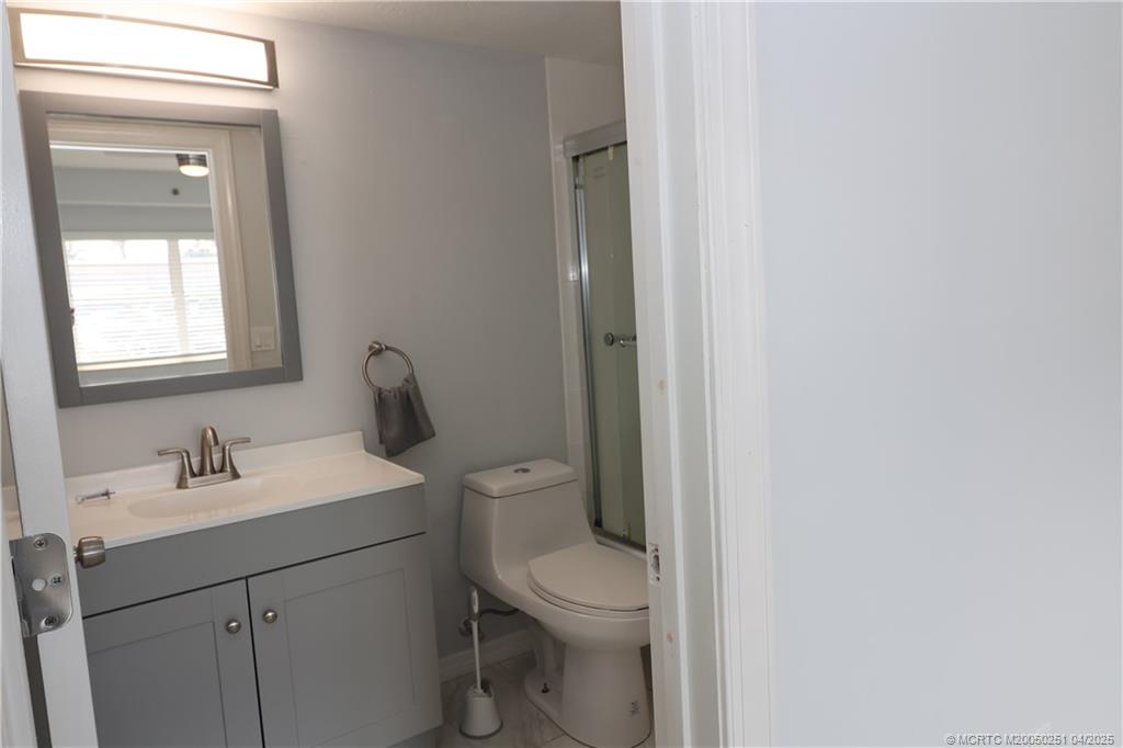 2950 Southeast Ocean Boulevard, Unit 101 Stuart, FL 34996 - Photo 25 of 35 a bathroom with a toilet a sink a mirror and vanity