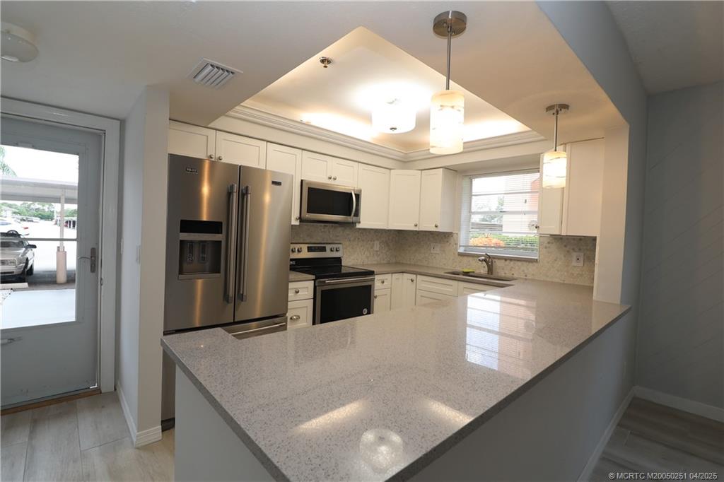 2950 Southeast Ocean Boulevard, Unit 101 Stuart, FL 34996 - Photo 3 of 35 a large kitchen with kitchen island a large counter top space appliances and cabinets