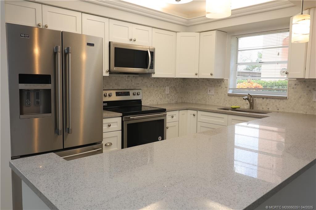 2950 Southeast Ocean Boulevard, Unit 101 Stuart, FL 34996 - Photo 4 of 35 a kitchen with stainless steel appliances a refrigerator sink and microwave
