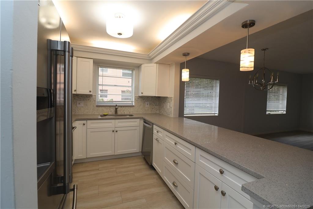 2950 Southeast Ocean Boulevard, Unit 101 Stuart, FL 34996 - Photo 8 of 35 a kitchen with granite countertop white cabinets white appliances a sink and a large window