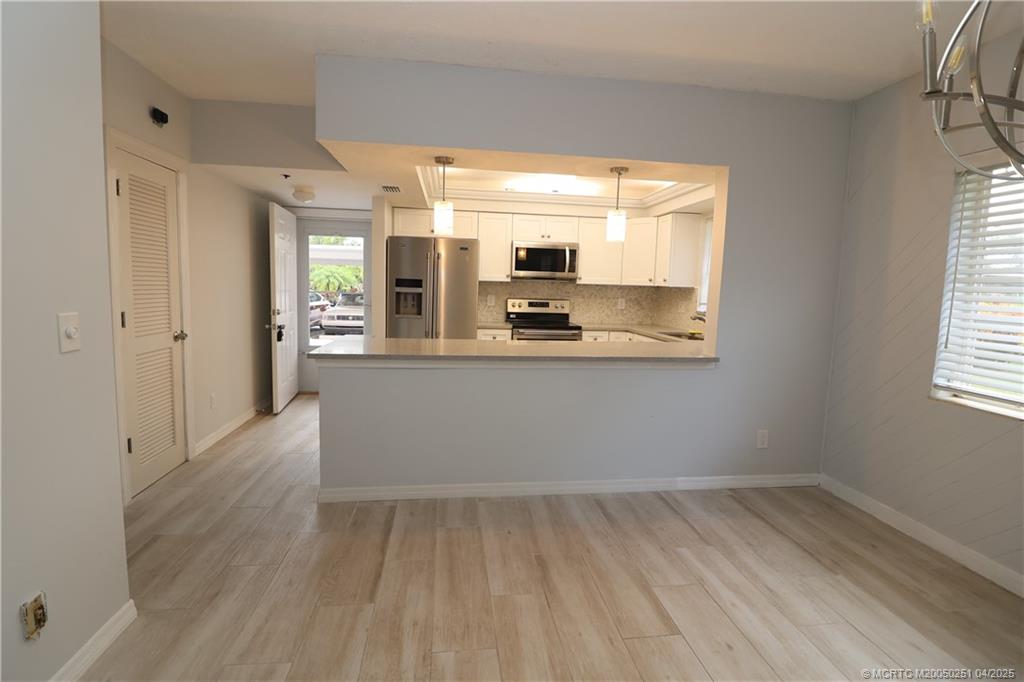 2950 Southeast Ocean Boulevard, Unit 101 Stuart, FL 34996 - Photo 9 of 35 a view of a kitchen with kitchen island a sink wooden floor and a large window