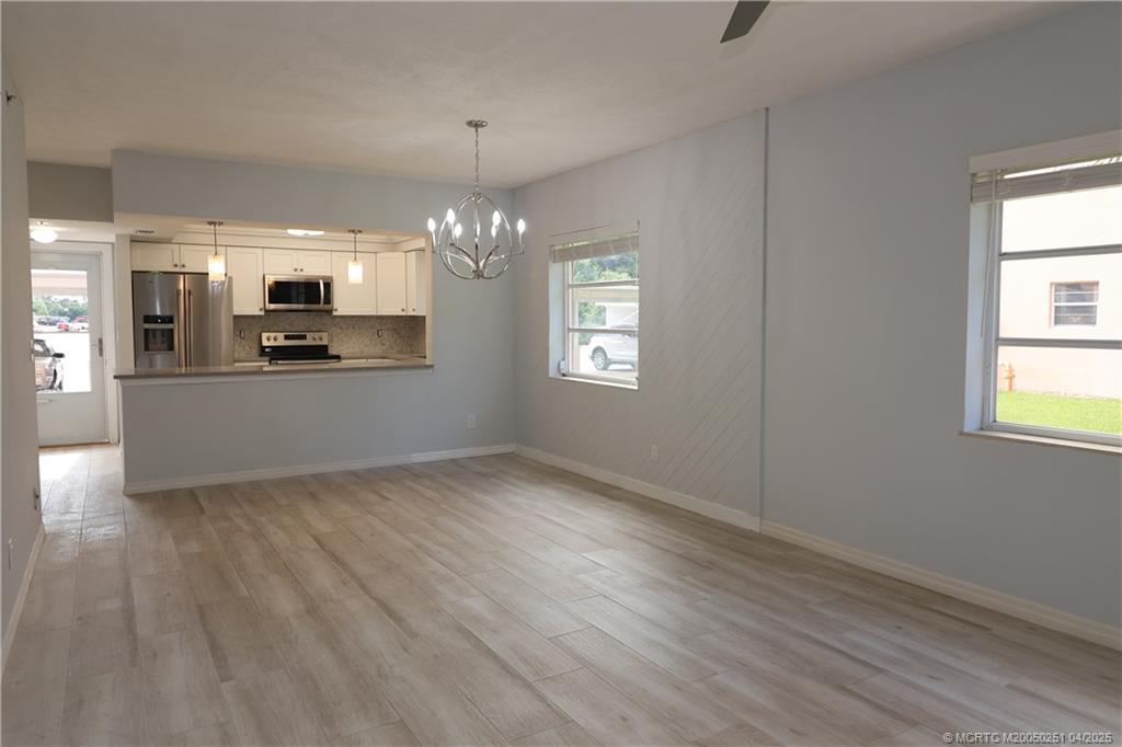 2950 Southeast Ocean Boulevard, Unit 101 Stuart, FL 34996 - Photo 10 of 35 an empty room with wooden floor chandelier and windows