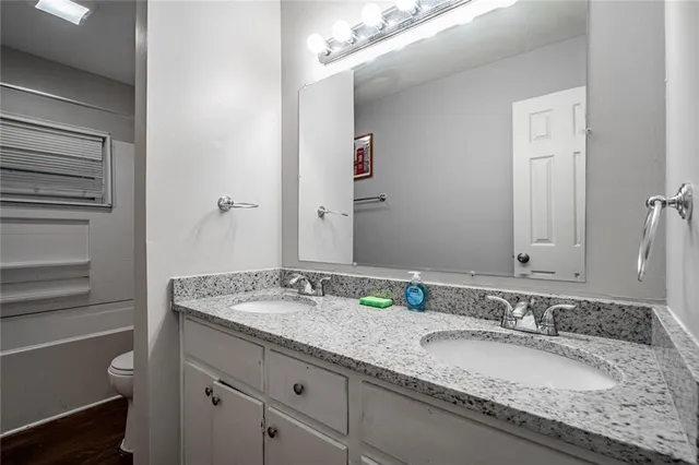 a bathroom with a granite countertop double vanity sink and a mirror