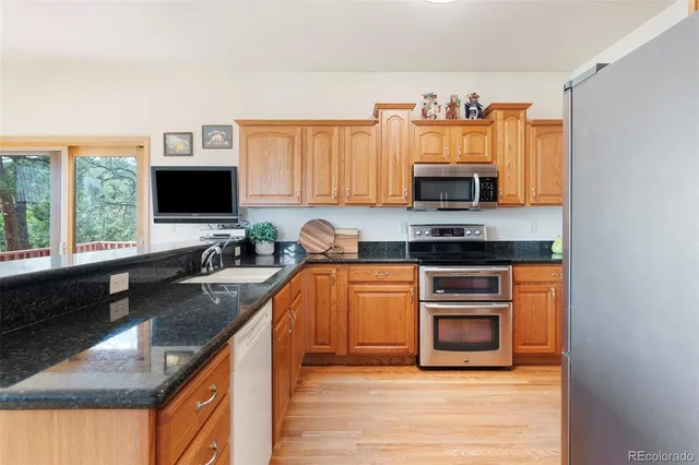 a kitchen with granite countertop a stove top oven a sink dishwasher and a microwave oven with large wooden cabinets