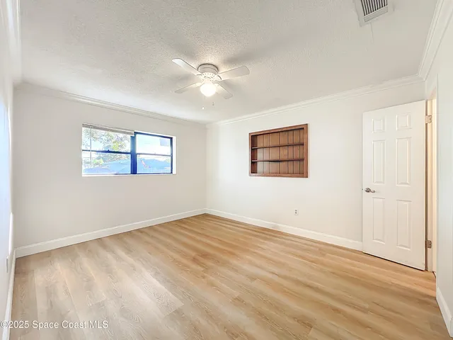 an empty room with wooden floor ceiling fan and windows