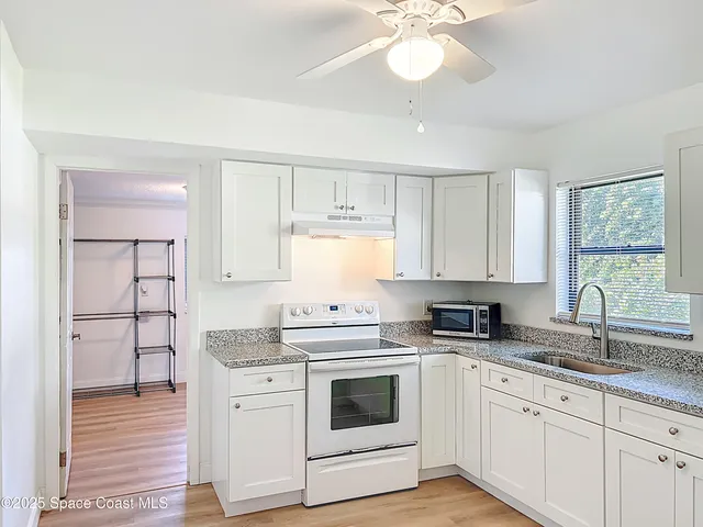 a kitchen with white cabinets appliances and a window