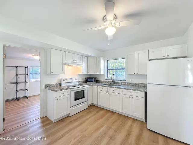 a kitchen with white cabinets appliances and chandelier