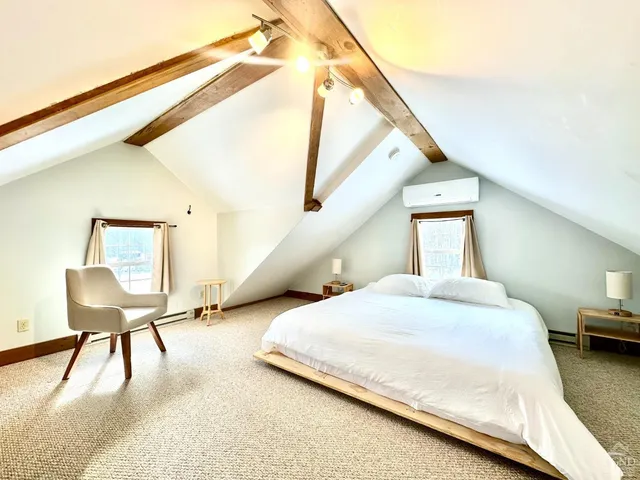 a bedroom with a bed a chair and potted plant on the table