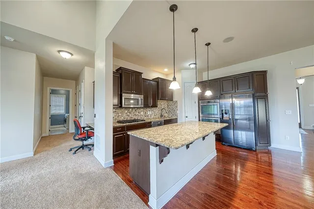 a kitchen with kitchen island granite countertop stainless steel appliances and wooden cabinets