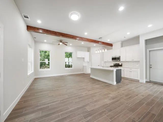 a large kitchen with white cabinets and wooden floor