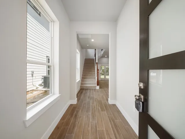 a view of a hallway with wooden floor and staircase