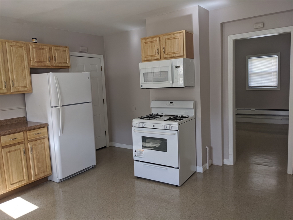 66 Batchelder Street, Unit 2 Boston, MA 02119 - Photo 3 of 8 a white refrigerator freezer and a stove sitting inside of a kitchen