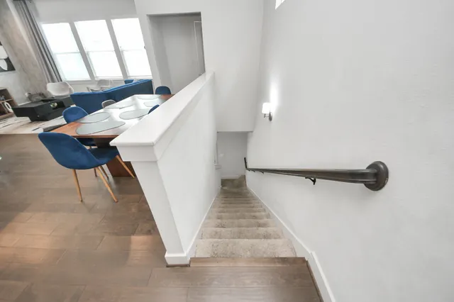 a living room with stainless steel appliances kitchen island granite countertop a stove a sink a refrigerator and a living room with wooden floor