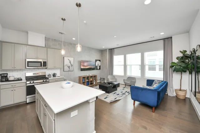 a kitchen with stainless steel appliances kitchen island granite countertop a stove a sink a dining table and chairs with wooden floor