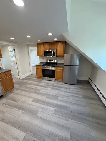 a view of kitchen with microwave refrigerator and wooden floor