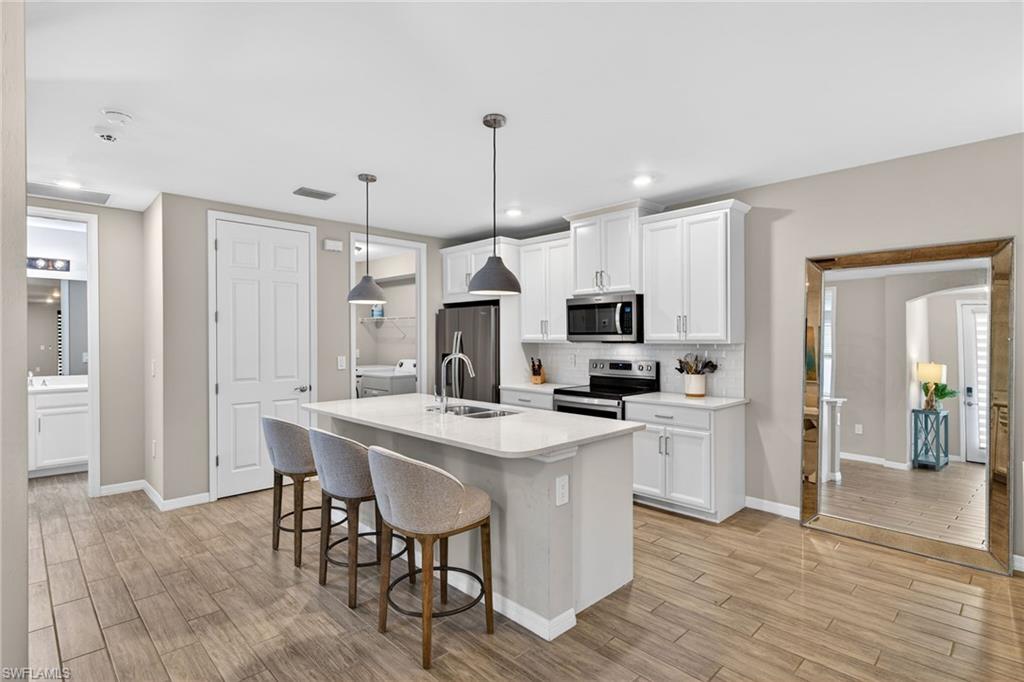 14567 Edgewater Circle Naples, FL 34114 - Photo 7 of 44 a kitchen with kitchen island white cabinets and stainless steel appliances