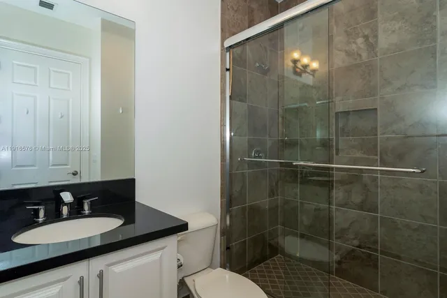a bathroom with a granite countertop sink a toilet and a mirror