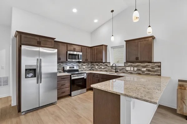a kitchen with granite countertop cabinets stainless steel appliances and wooden floor