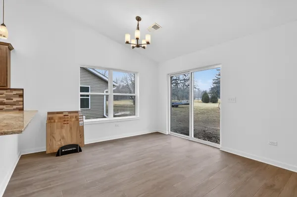 a kitchen with stainless steel appliances kitchen island granite countertop a dishwasher a stove a refrigerator and white cabinets with wooden floor