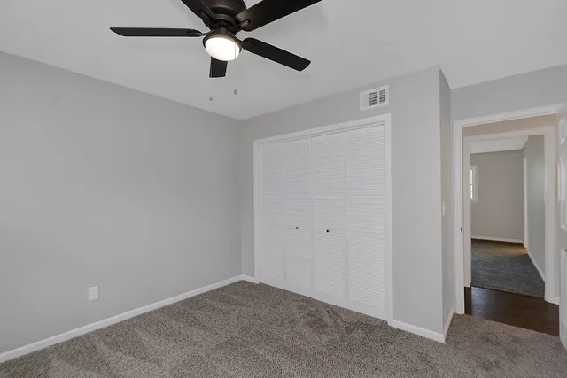 an empty room with closet and a chandelier fan