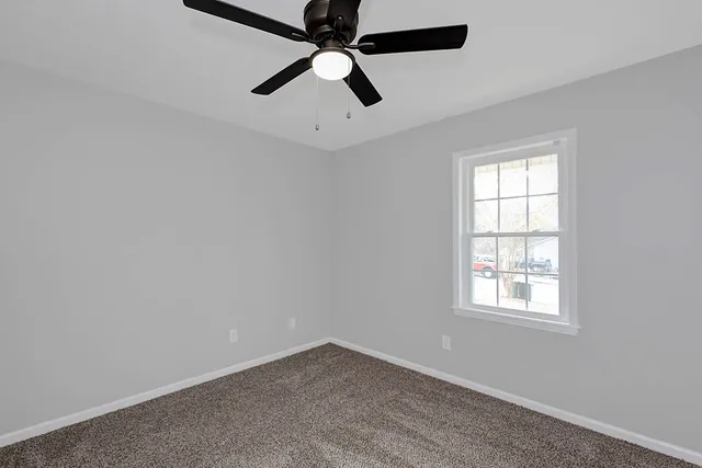 an empty room with a window and a fan