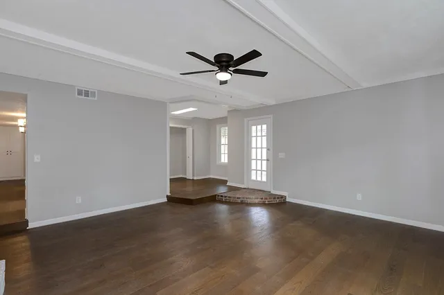 a view of an empty room with window and wooden floor