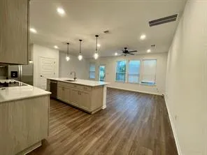 a large kitchen with a sink and wooden floor