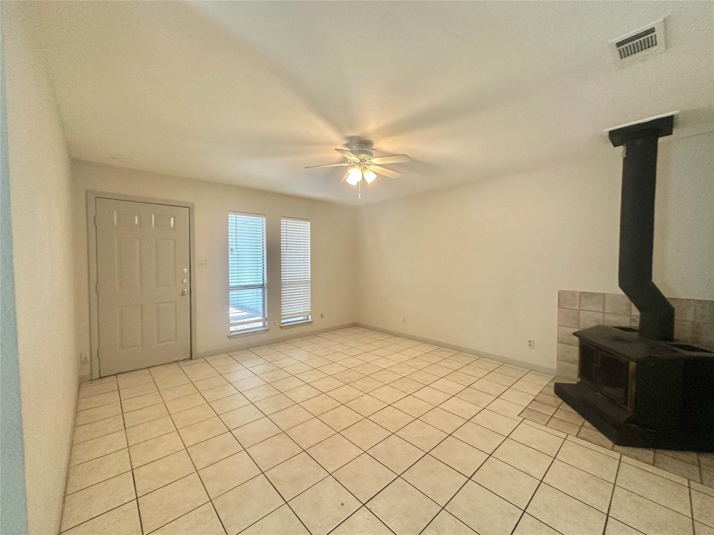 11907 Argonne Forest Trail, Unit B Austin, TX 78759 - Photo 6 of 11 Unfurnished living room with a wood stove, ceiling fan, and light tile patterned floors