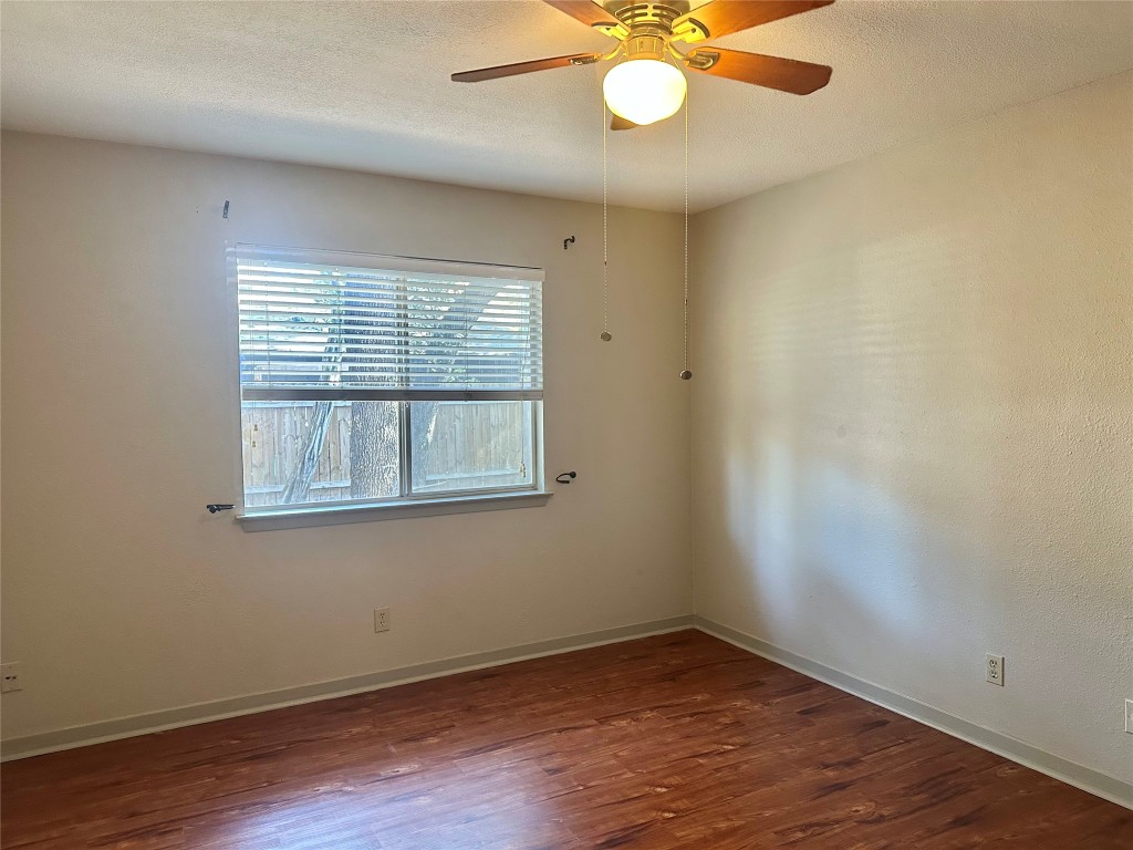 11907 Argonne Forest Trail, Unit B Austin, TX 78759 - Photo 7 of 11 Spare room featuring a textured ceiling, dark wood finished floors, and a ceiling fan