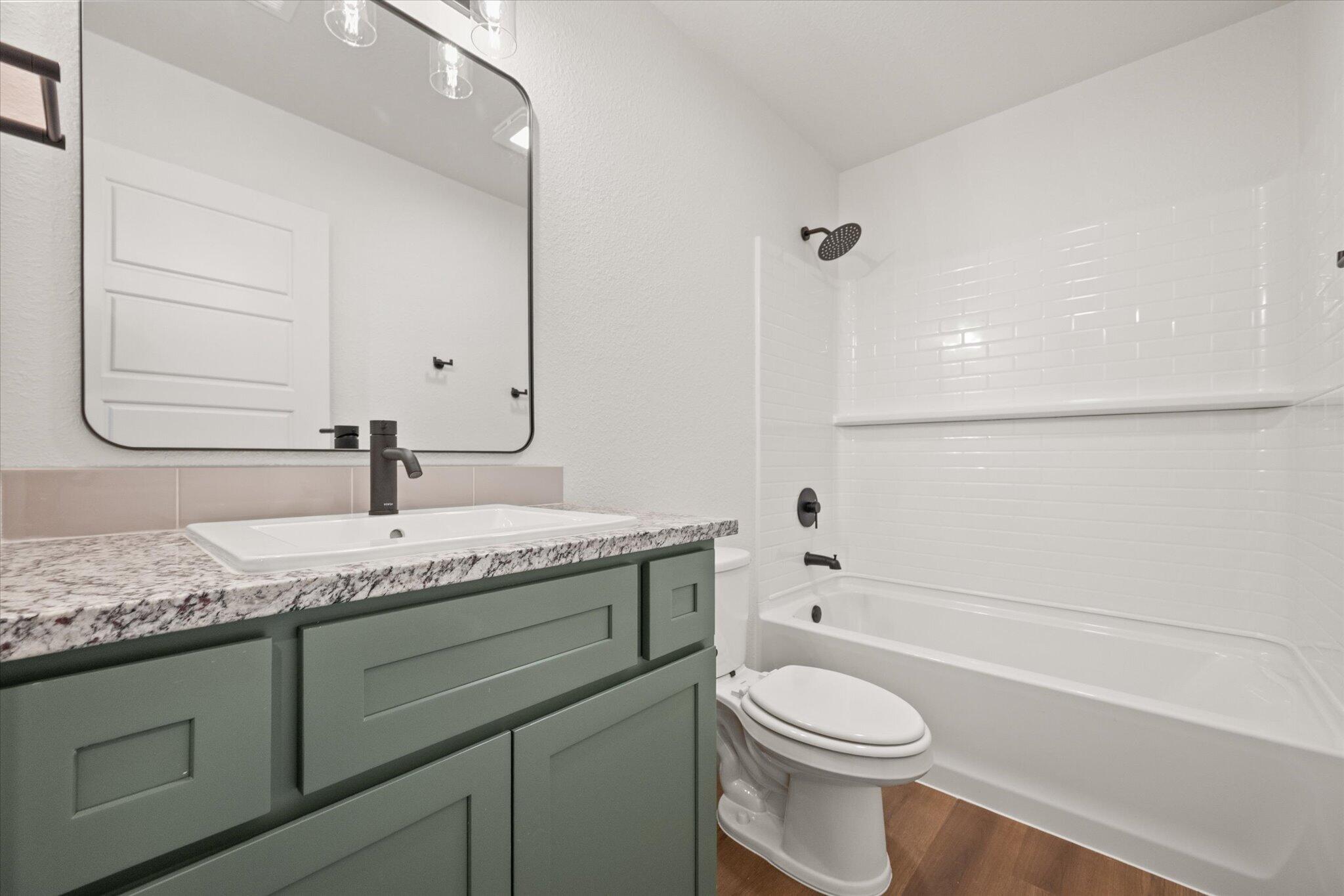 7111 14th Street Lubbock, TX 79416 - Photo 23 of 25 a bathroom with a granite countertop toilet sink and mirror
