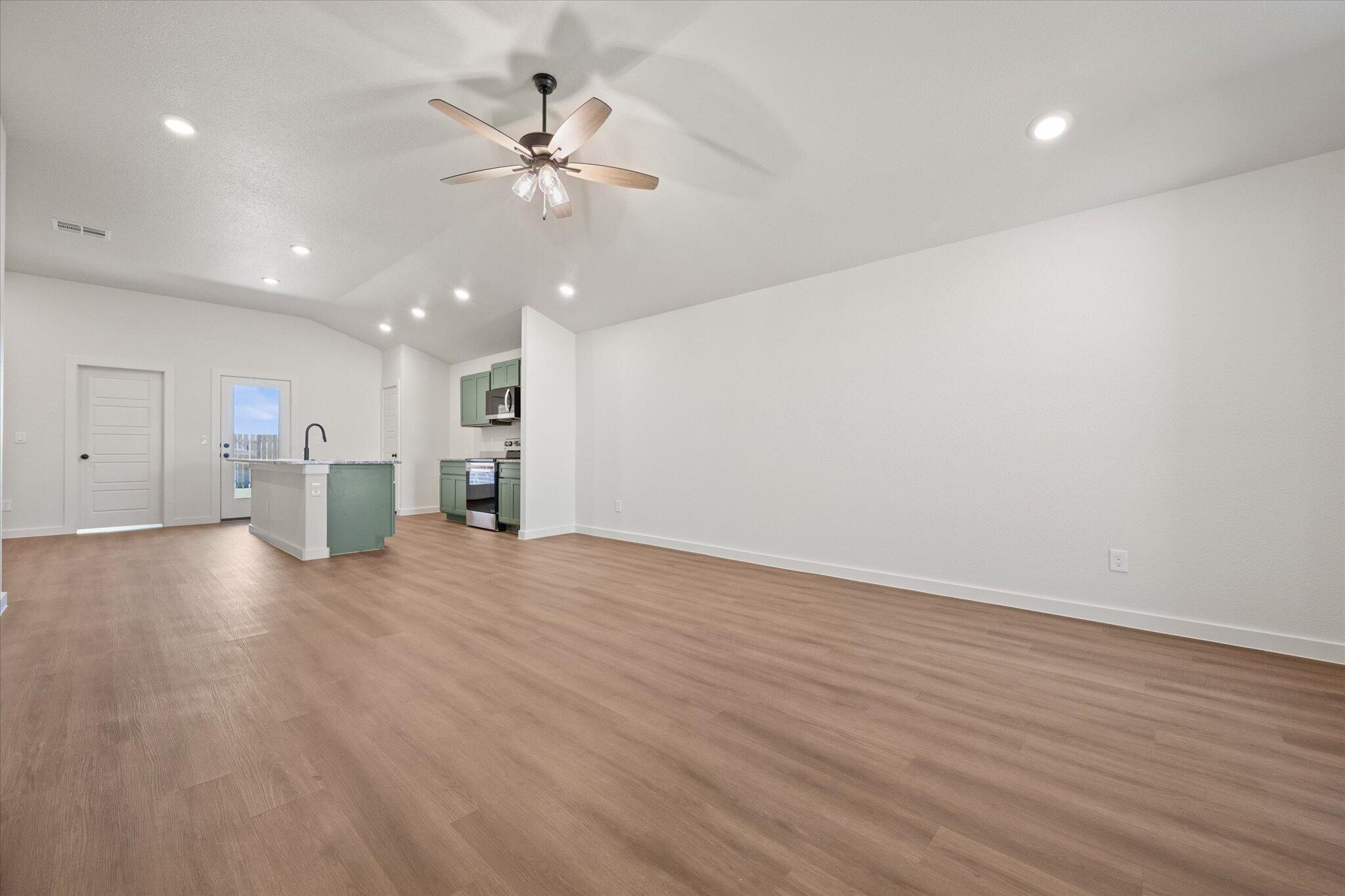 7111 14th Street Lubbock, TX 79416 - Photo 4 of 25 a view of an empty room with wooden floor and a ceiling fan