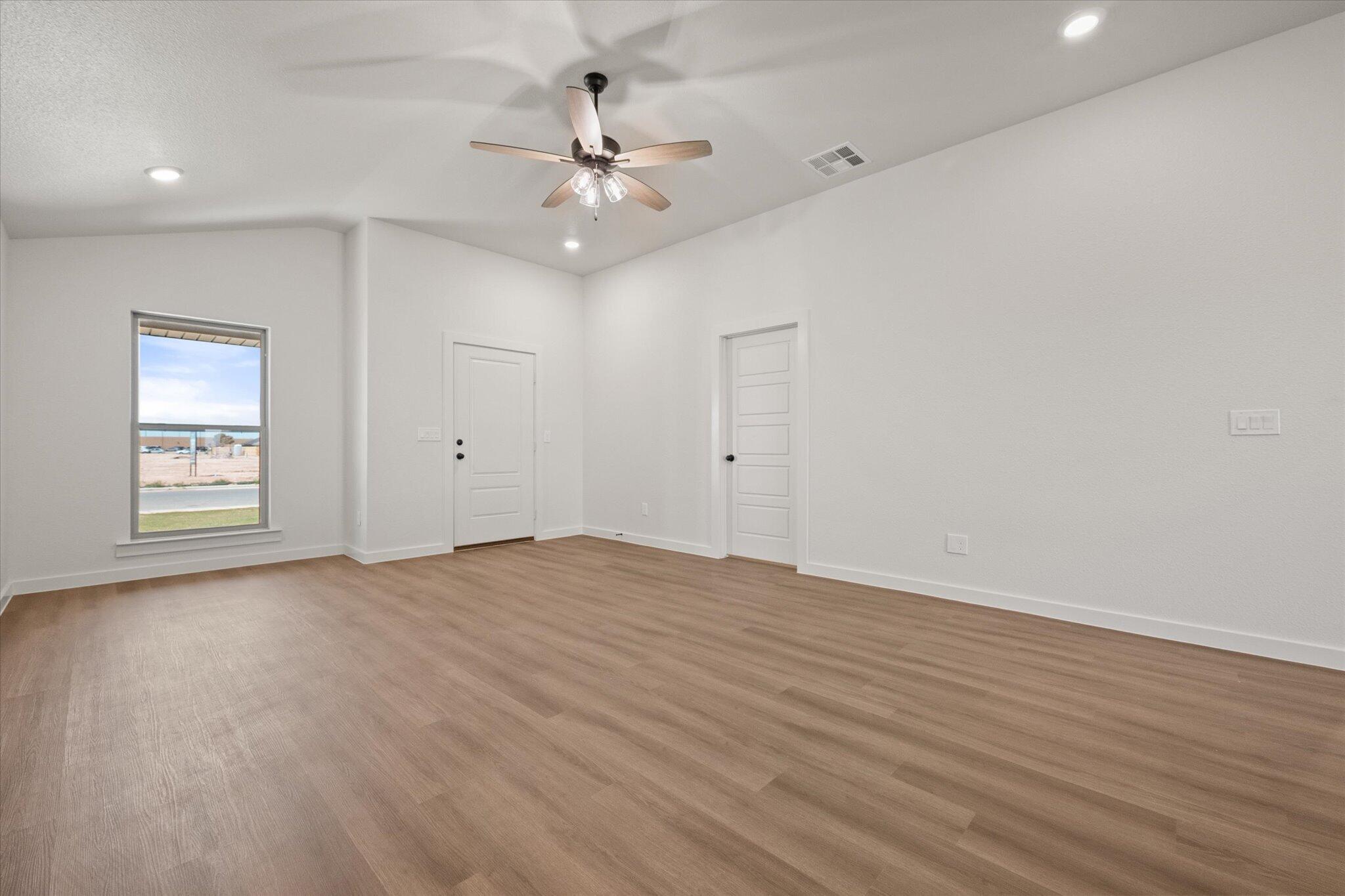 7111 14th Street Lubbock, TX 79416 - Photo 6 of 25 a view of an empty room with chandelier fan and wooden floor