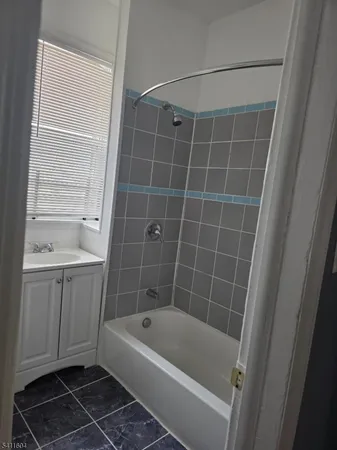 a bathroom with a tub a sink a window and a shower