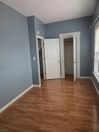 a view of an empty room with wooden floor and window
