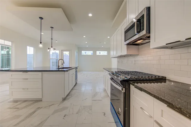 a kitchen with stainless steel appliances granite countertop a sink a stove and a wooden floors