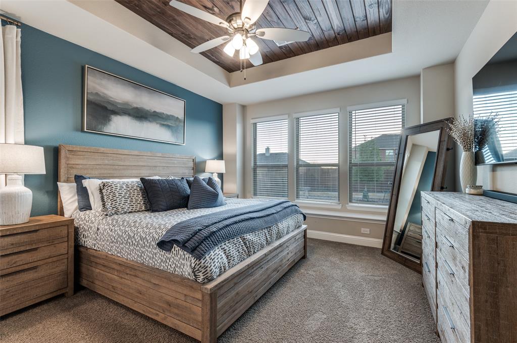 425 Acadia Lane Forney, TX 75126 - Photo 24 of 37 a spacious bedroom with a large bed and a chandelier