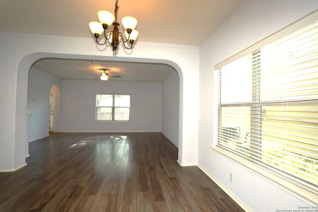 a view of empty room with wooden floor and fan