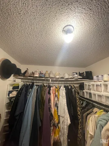 a view of walk in closet with clothes and shoes