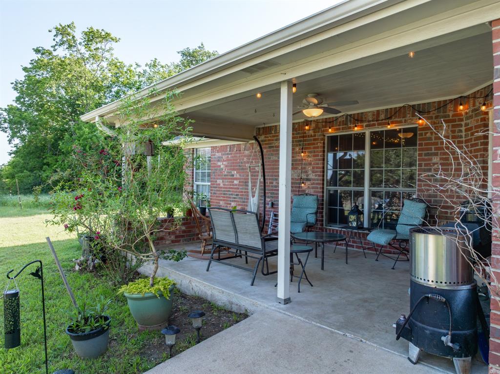 4037 Old Dallas Road Elm Mott, TX 76640 - Photo 28 of 40 a view of a patio with table and chairs potted plants and floor to ceiling window
