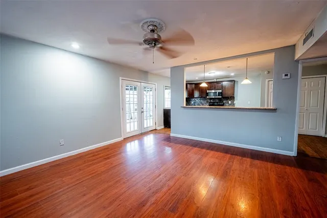 a view of a livingroom with wooden floor and kitchen