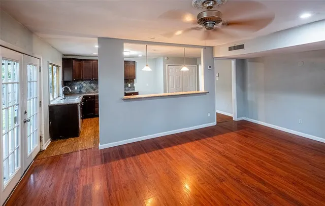 a view of empty room with wooden floor and fan