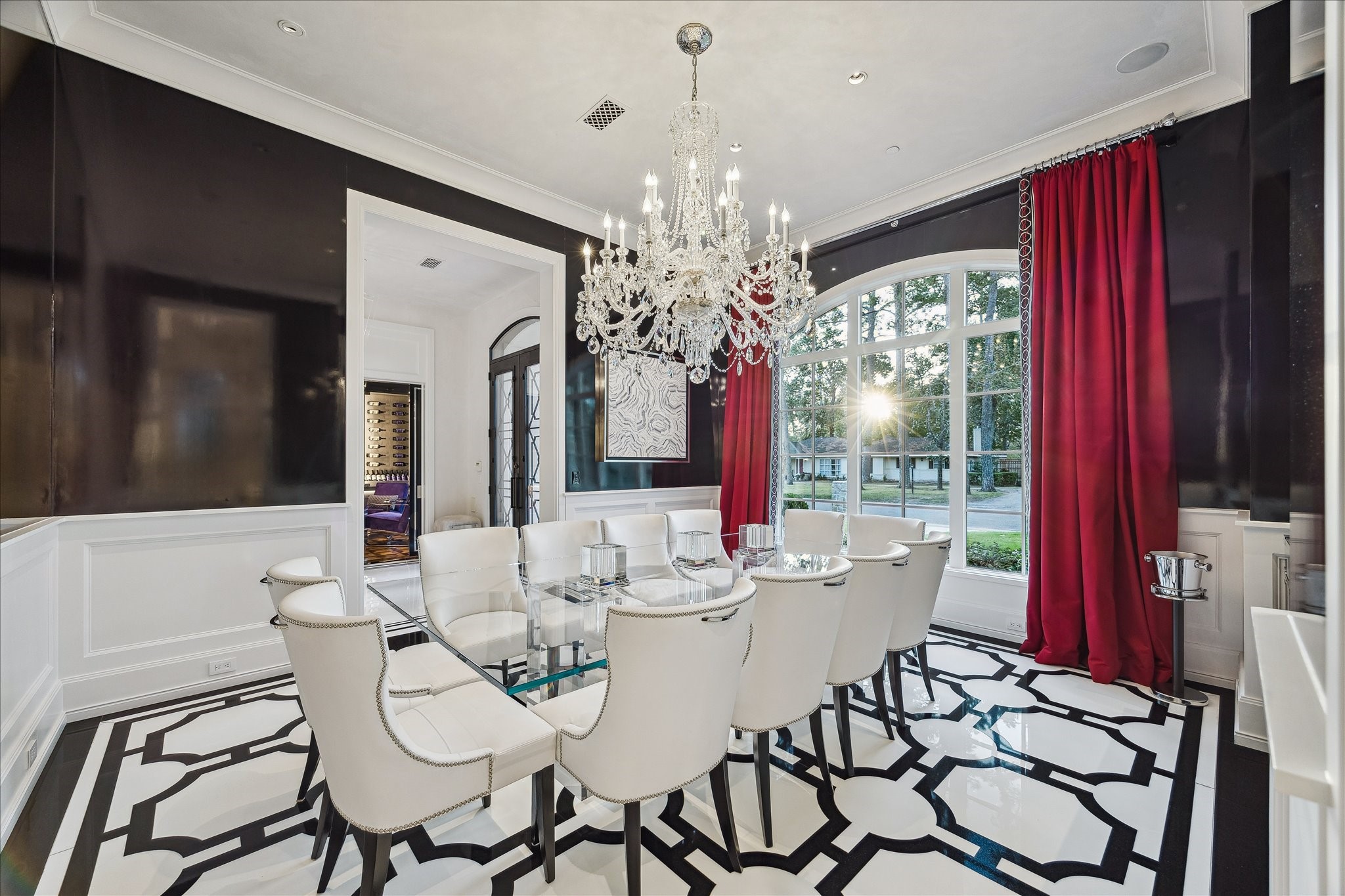 220 Merrie Way Lane Houston, TX 77024 - Photo 5 of 50 A showpiece for entertaining, the formal dining room features high-gloss white tile with bold black granite inlays, all centered beneath a statement crystal chandelier. Custom lacquered walls, Segreto-plastered ceilings, and art-focused lighting create a refined backdrop.