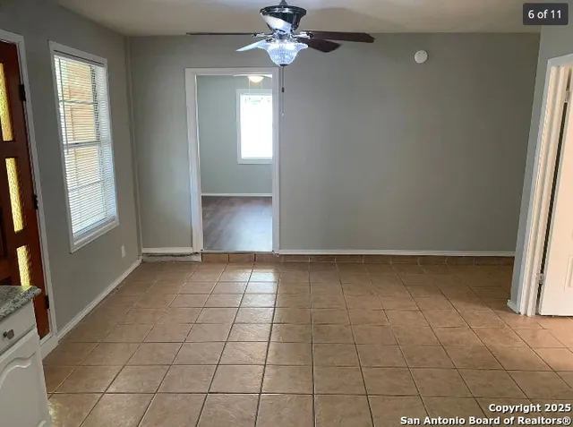a view of an empty room with window and chandelier fan