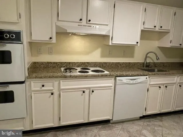 a kitchen with granite countertop white cabinets and a stove