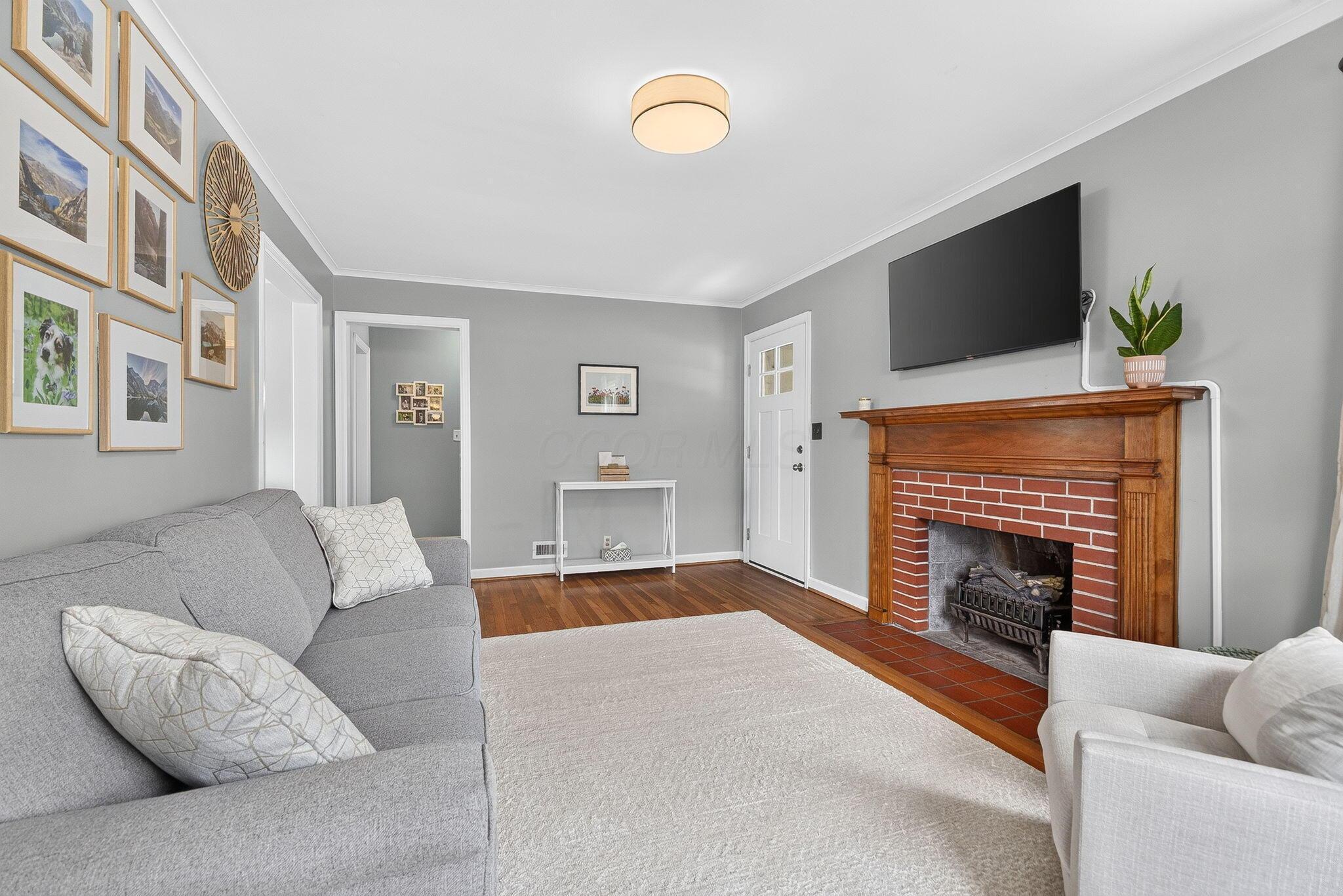 492 Wetmore Road Columbus, OH 43214 - Photo 15 of 55 Living area featuring wood-finish flooring, a white door with divided lites, and a brick fireplace with a wood mantel