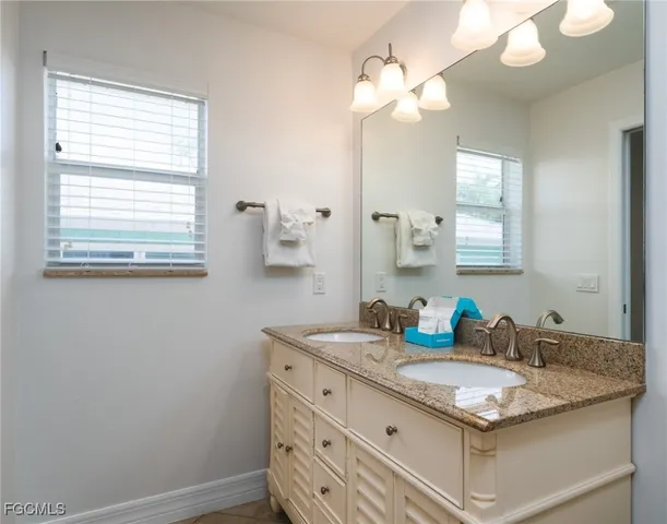 a bathroom with a granite countertop sink a light fixture and a mirror