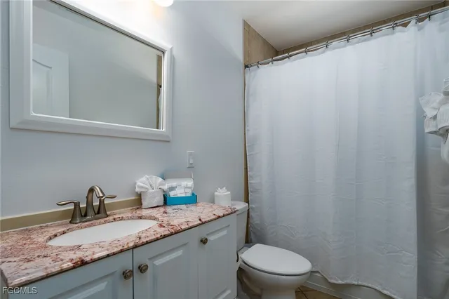 a bathroom with a granite countertop sink toilet and a mirror